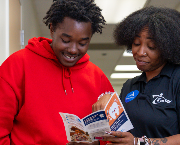 Photo of two people reviewing a pamphlet in a hallway next to a bulletin board.