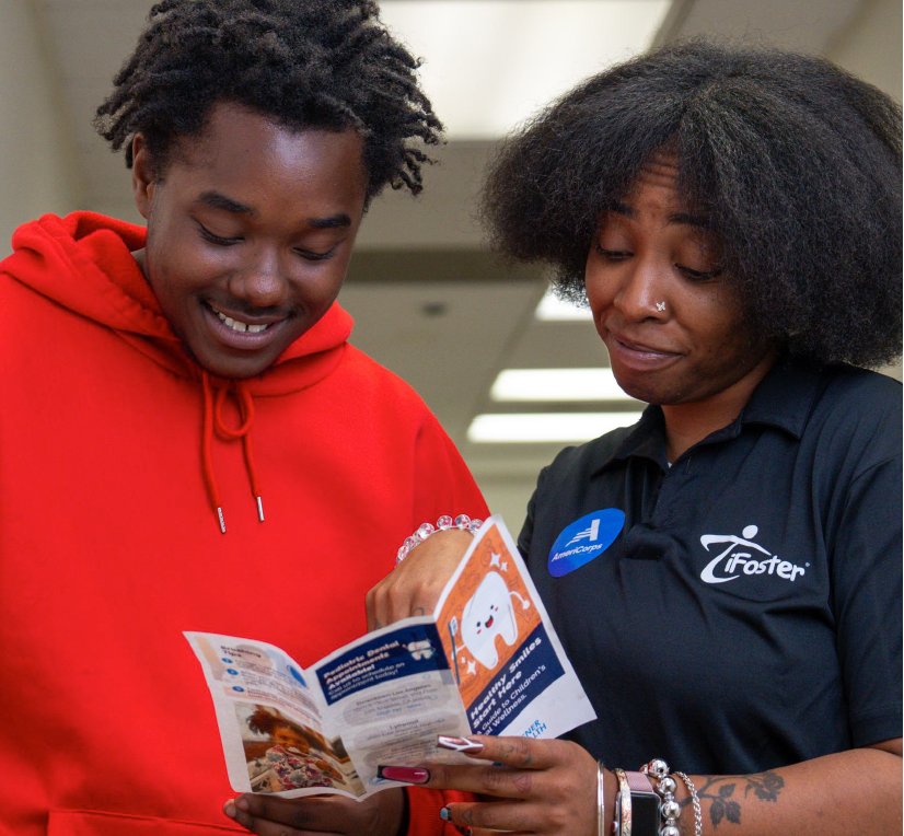 Photo of two people reviewing a pamphlet in a hallway next to a bulletin board.